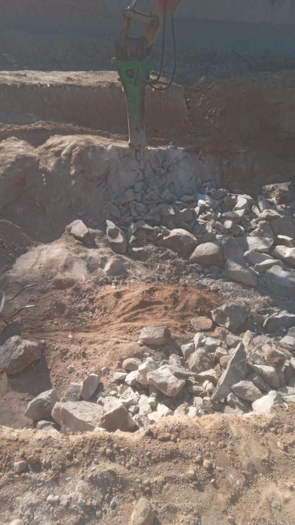 Excavator breaking concrete rubble debris